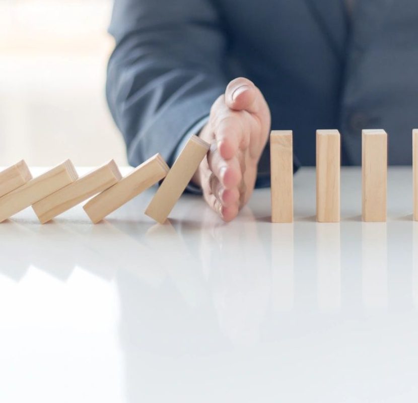 A person stopping the domino effect on a table.